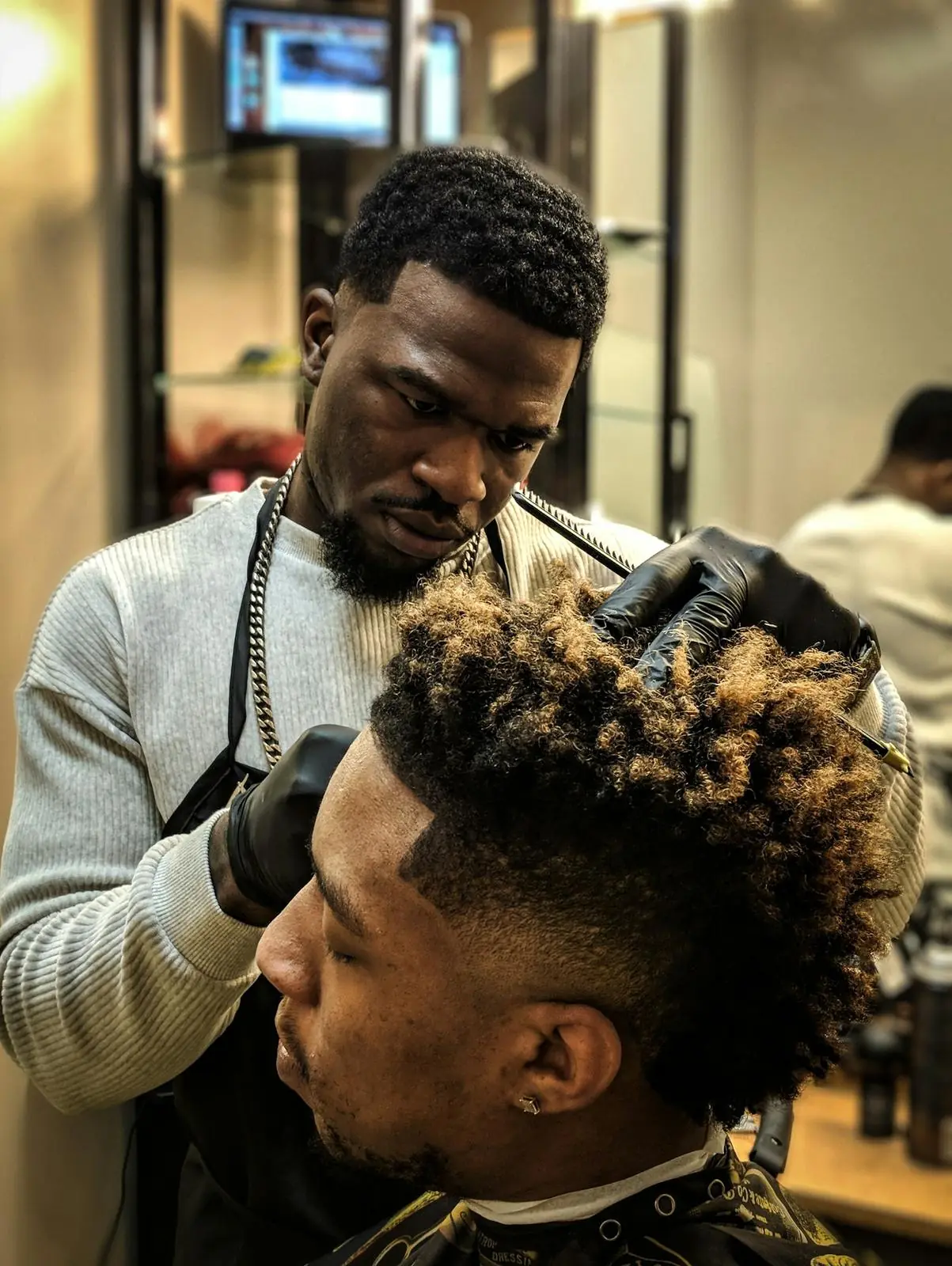 Barber detailing a high skin fade with a curly top