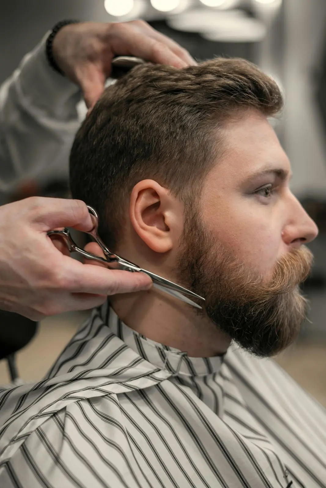 Barber shaping a full beard with scissors and comb