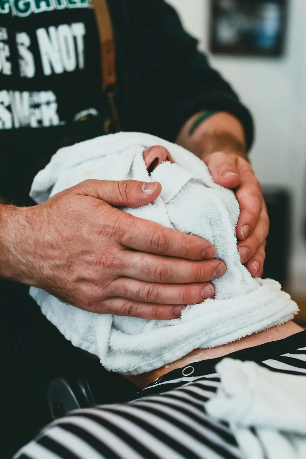 Barber pressing a hot towel over a client's face