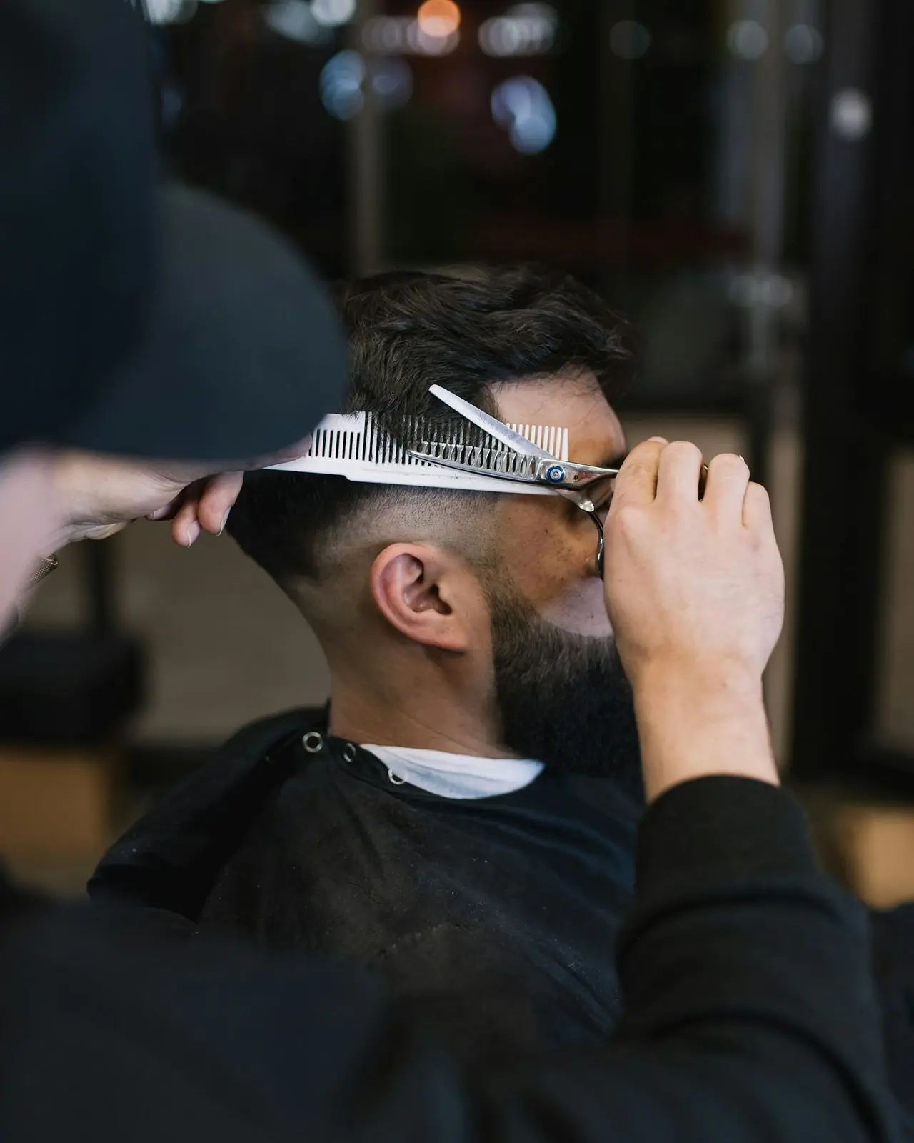 Barber blending a mid fade with comb and shears