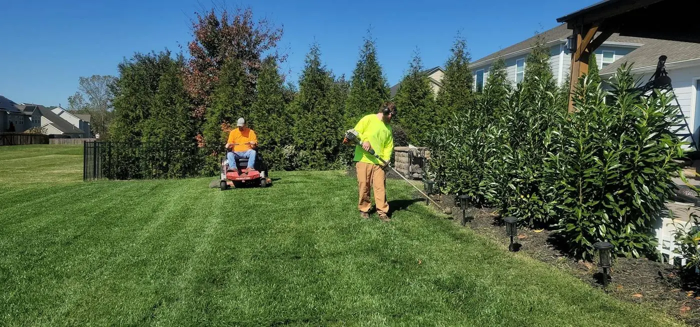 Crew mowing stripes into a large lawn with a riding mower