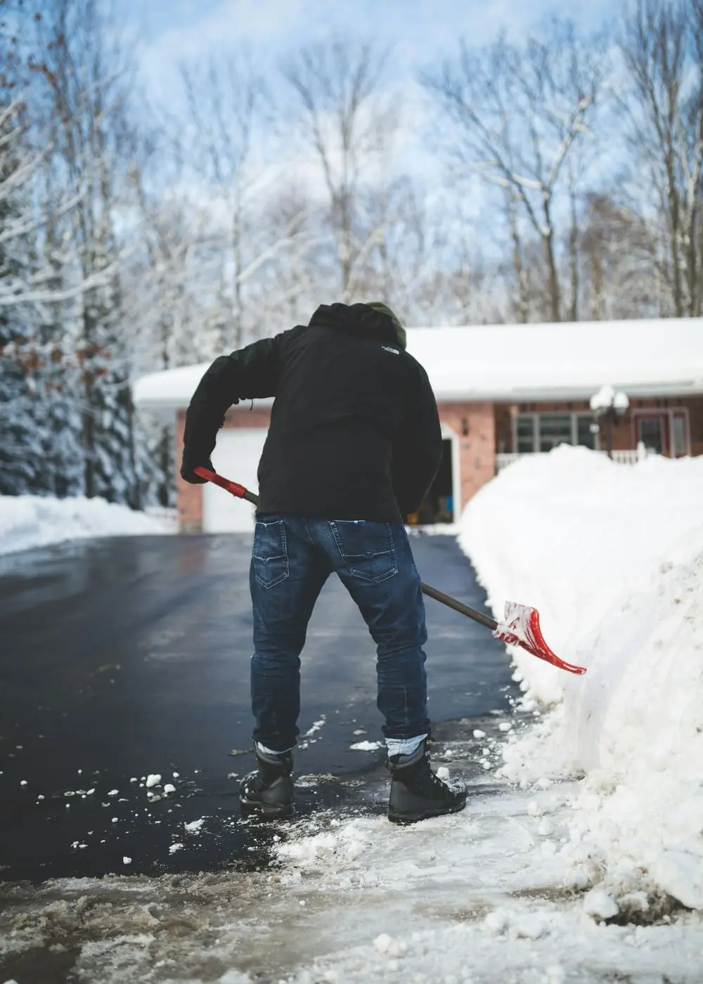 Person shoveling deep snow off a residential driveway