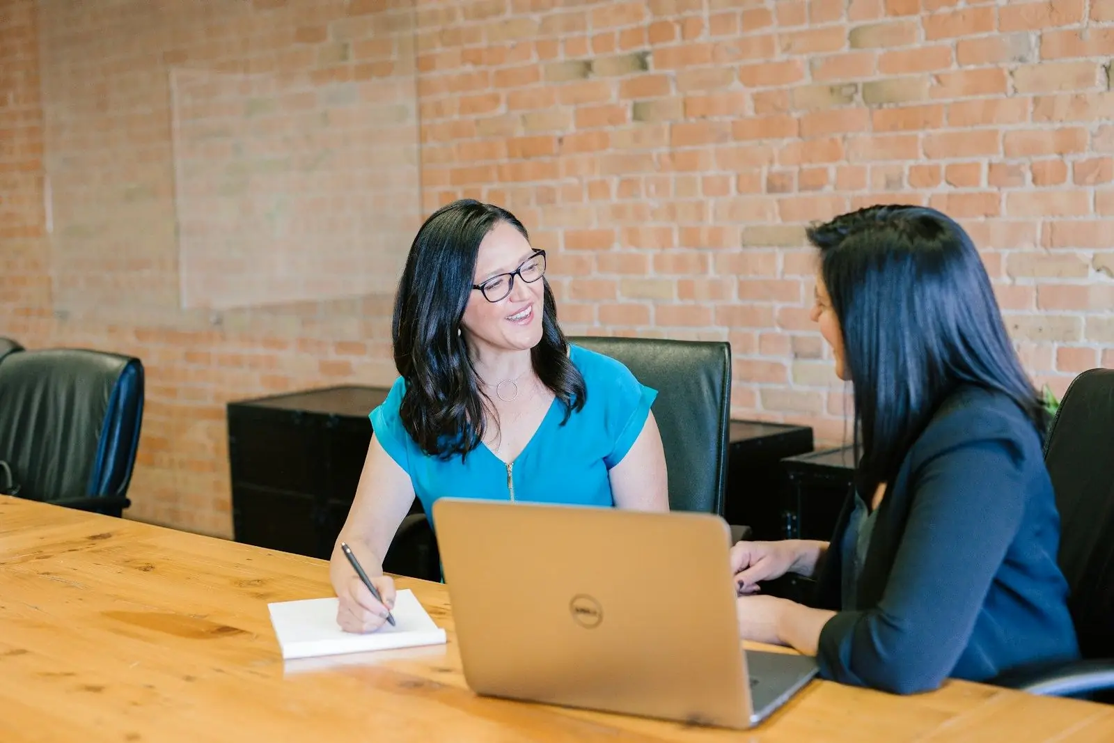 An advisor talking with a client across a desk with a laptop