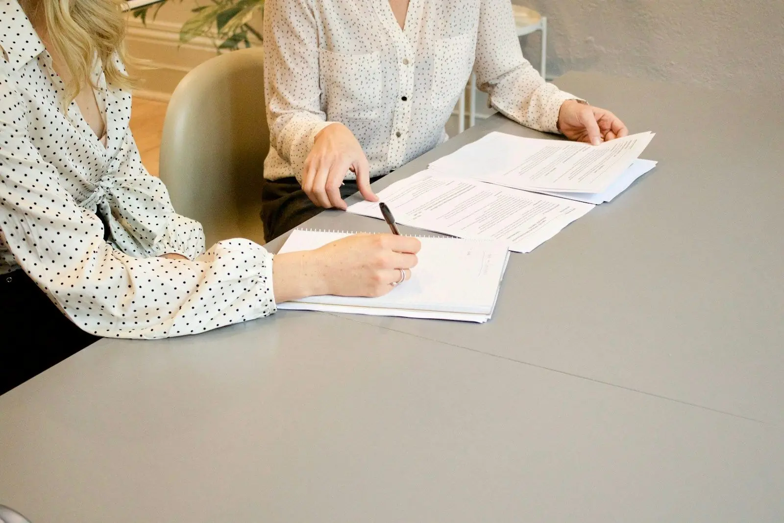 Hands signing a document at a table