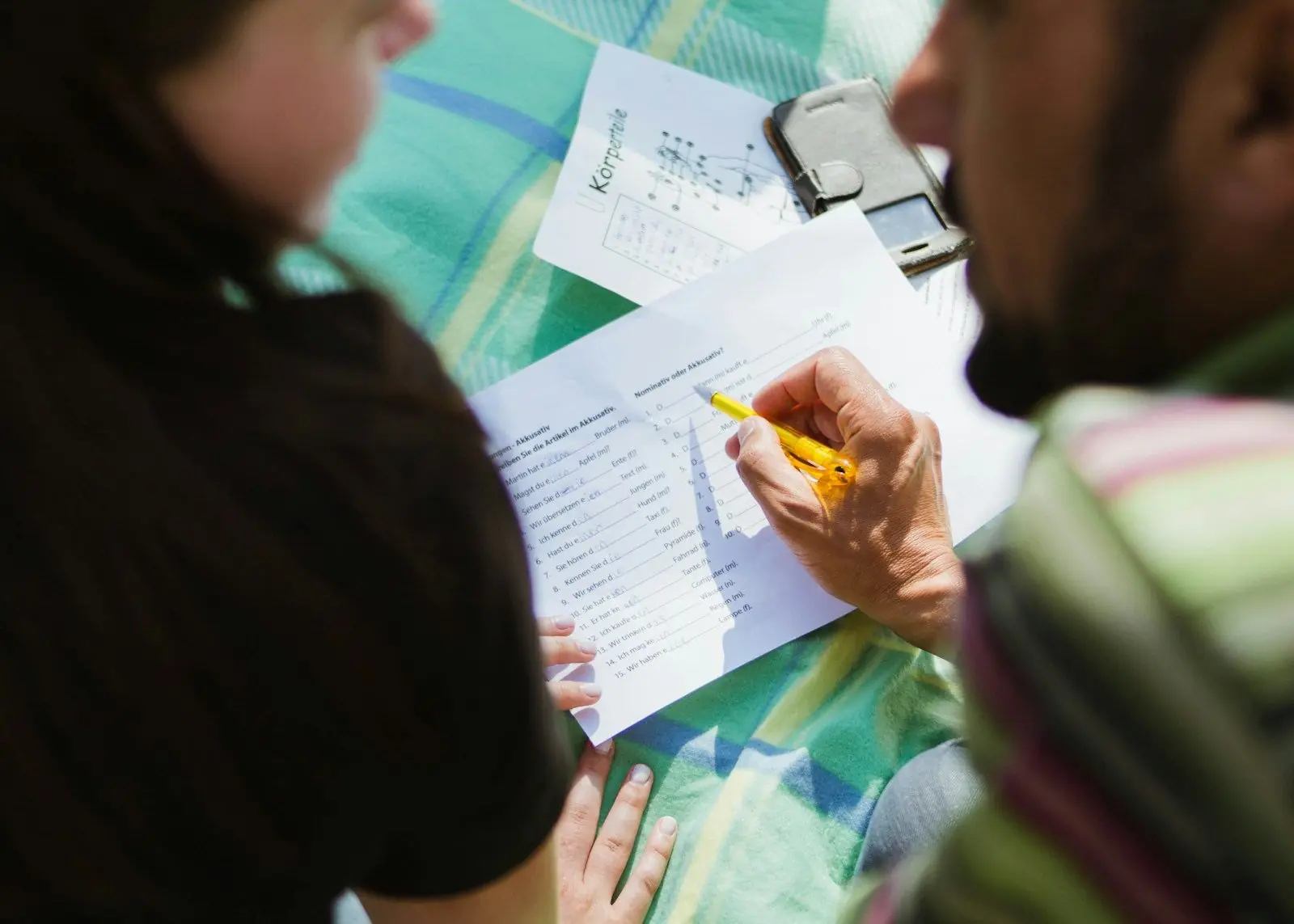 Two people going over a printed form together, one pointing with a pencil